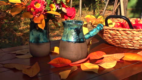 mesa de acción de gracias con cesta de mimbre llena de nueces, granadas rojas y flores frescas