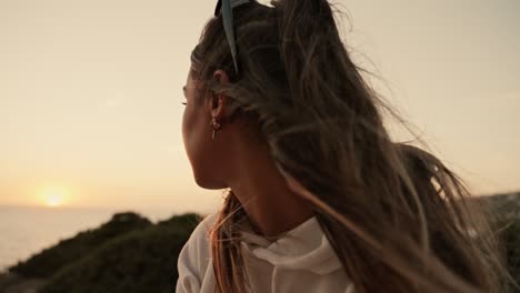 slow motion shot of a beautiful female model watching the sunset over the sea