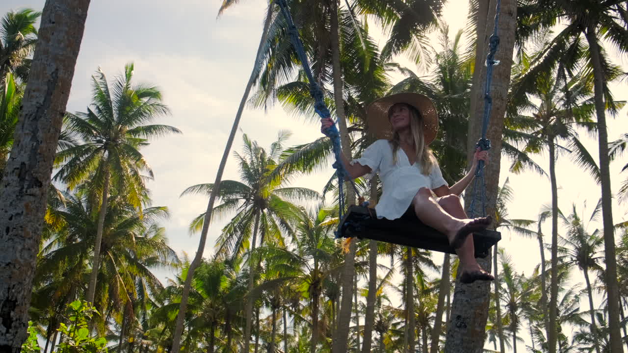 mujer balanceándose en las palmeras