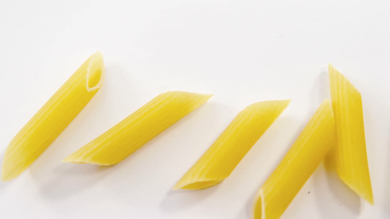 pasta de penne dispersada sobre un fondo blanco