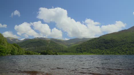 white clouds billowing over forested mountainsides next to lake ennerdale water on sunny summer day