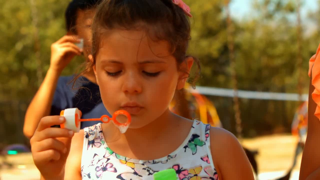 primer plano de escolares jugando con una varita de burbujas