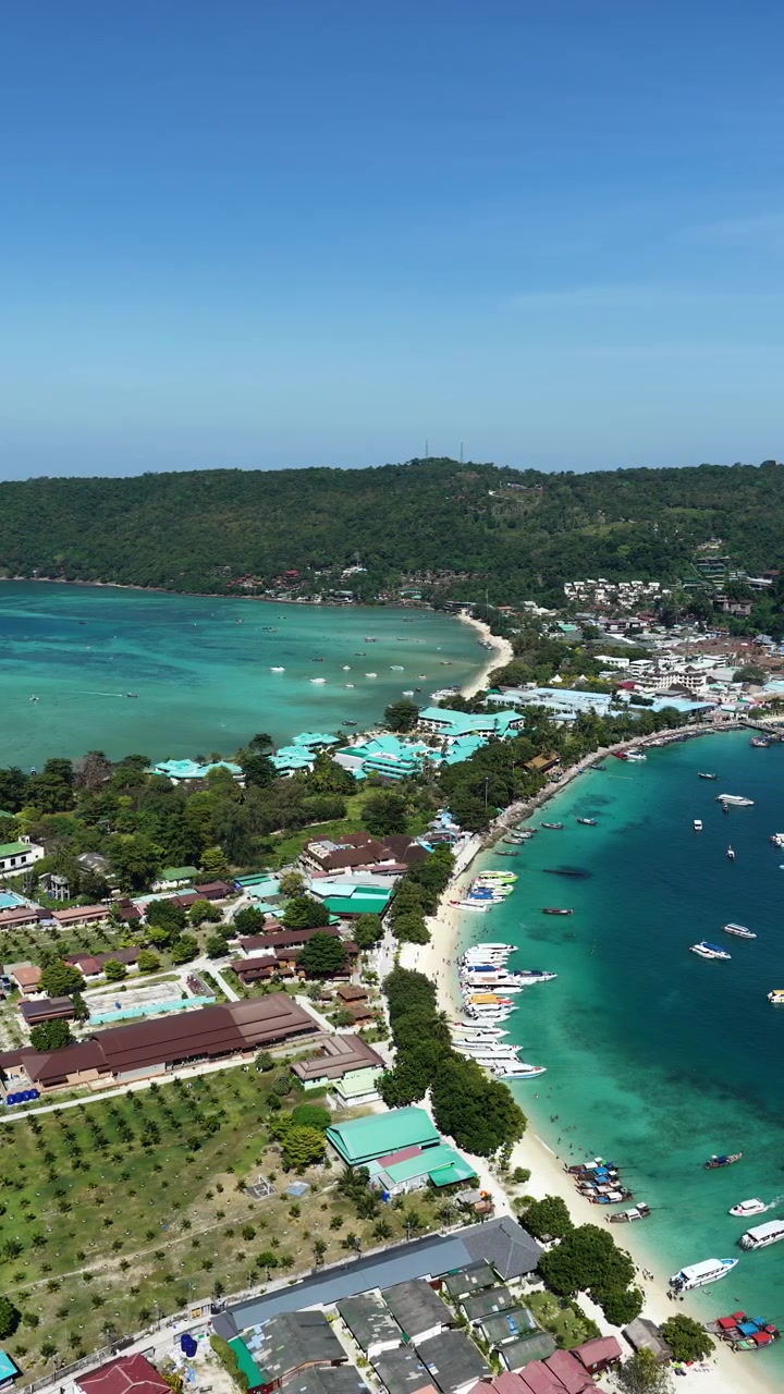 Ripresa aerea verticale della costa di Phi Phi Don con spiagge e baie turchesi, con il drone che si sposta verso destra sullo sfondo.
