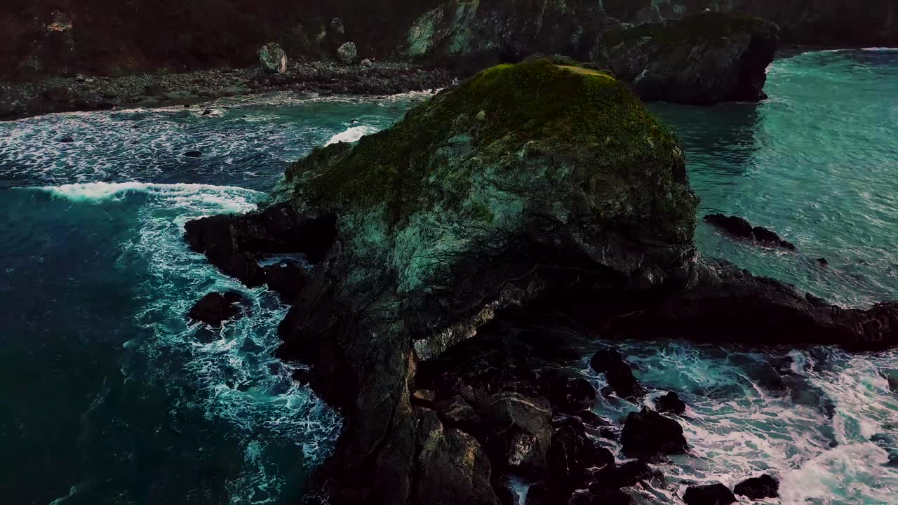 Ripresa aerea in ascesa di una grotta scavata nella roccia oceanica dalle onde che si infrangono a Sand Dollar Beach a Big Sur, California.