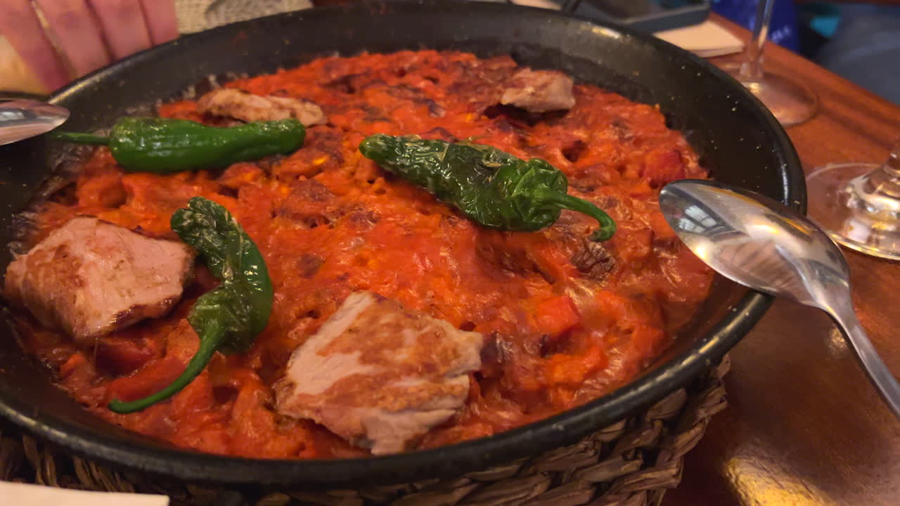 Delicious meat paella with green padron peppers at a Spanish restaurant in Sevilla Spain, traditional Spanish food, famous rice dish, 4K shot