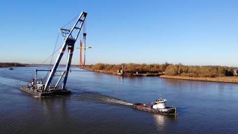 tugboat and floating sheerleg sailing at the river in barendrecht, netherlands