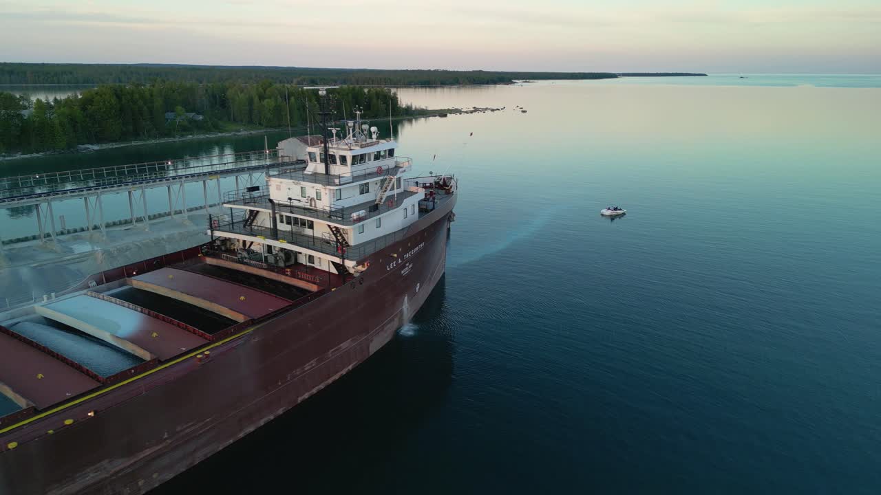 Aerial orbit view of great lakes freighter bow on flat water, lake huron