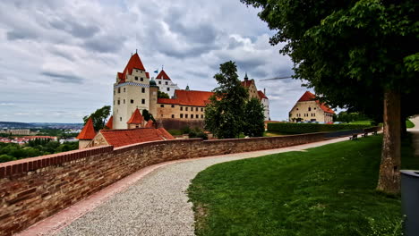 wide path curves along trausnitz castle wall with red roofs and green summer lawn