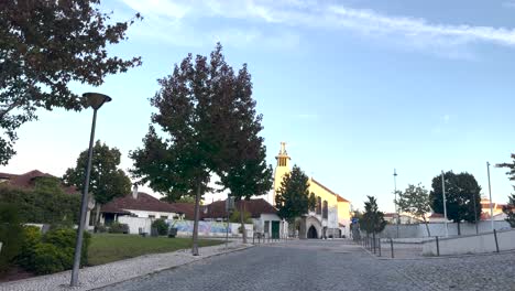 static shot of lisbon neighbourhood and catholic church with moon in backdrop in portugal