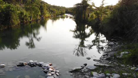 Flying-low-over-a-river-swimming-area-at-sunset