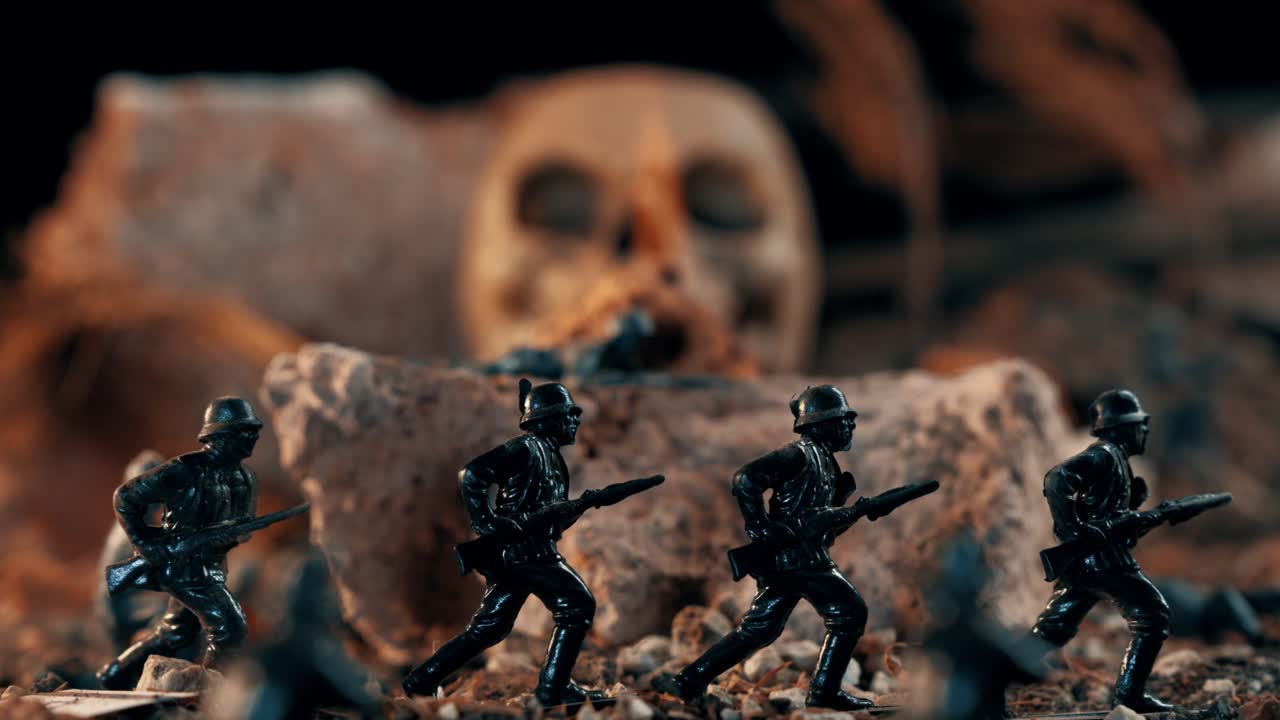 Ripresa macro di soldatini tedeschi che corrono attraverso un diorama di un campo di battaglia. Un teschio umano appare minacciosamente sullo sfondo a simboleggiare la morte.