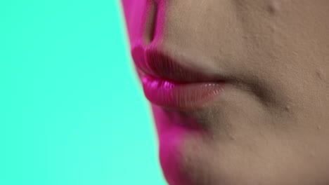 mujer comiendo una frambuesa en primer plano, esmalte de uñas femenino y labios de lápiz labial rojo en fondo verde