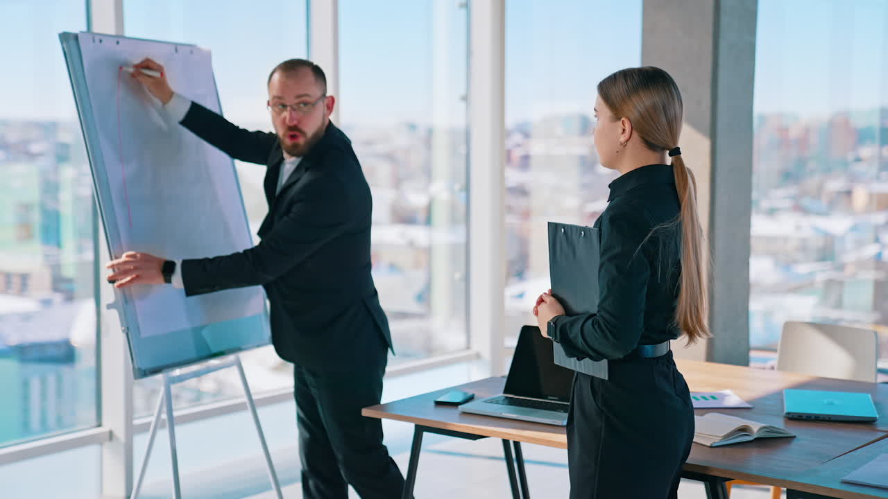 Creative designer drawing on white board. Male manager working on new blueprint in office room. Beautiful business woman listens to new ideas of coworker.