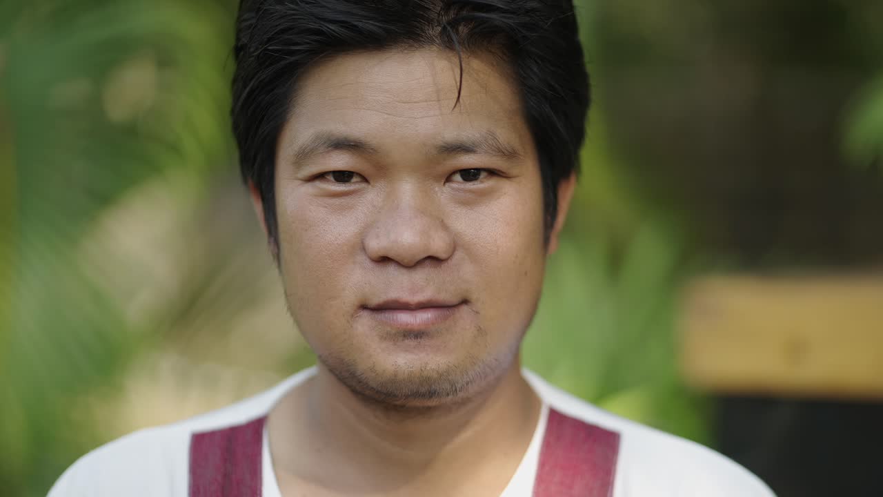 Close-up portrait of a smiling Asian man outdoors