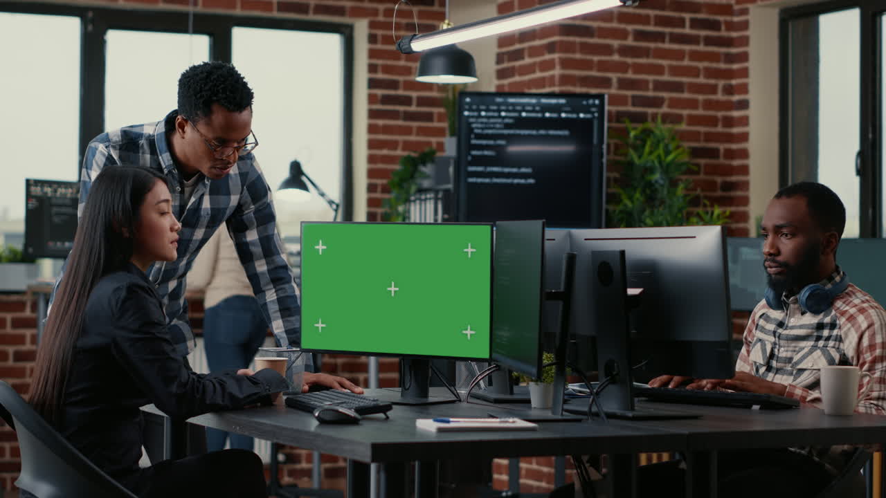 Two software developers analyzing source code looking at green screen chroma key mockup with coworker sitting at desk