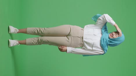 cuerpo lleno de mujer musulmana asiática que tiene dolor de cabeza mientras está de pie en el estudio de fondo de la pantalla verde