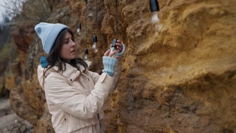 Woman installing hanging lights on a rock cliff