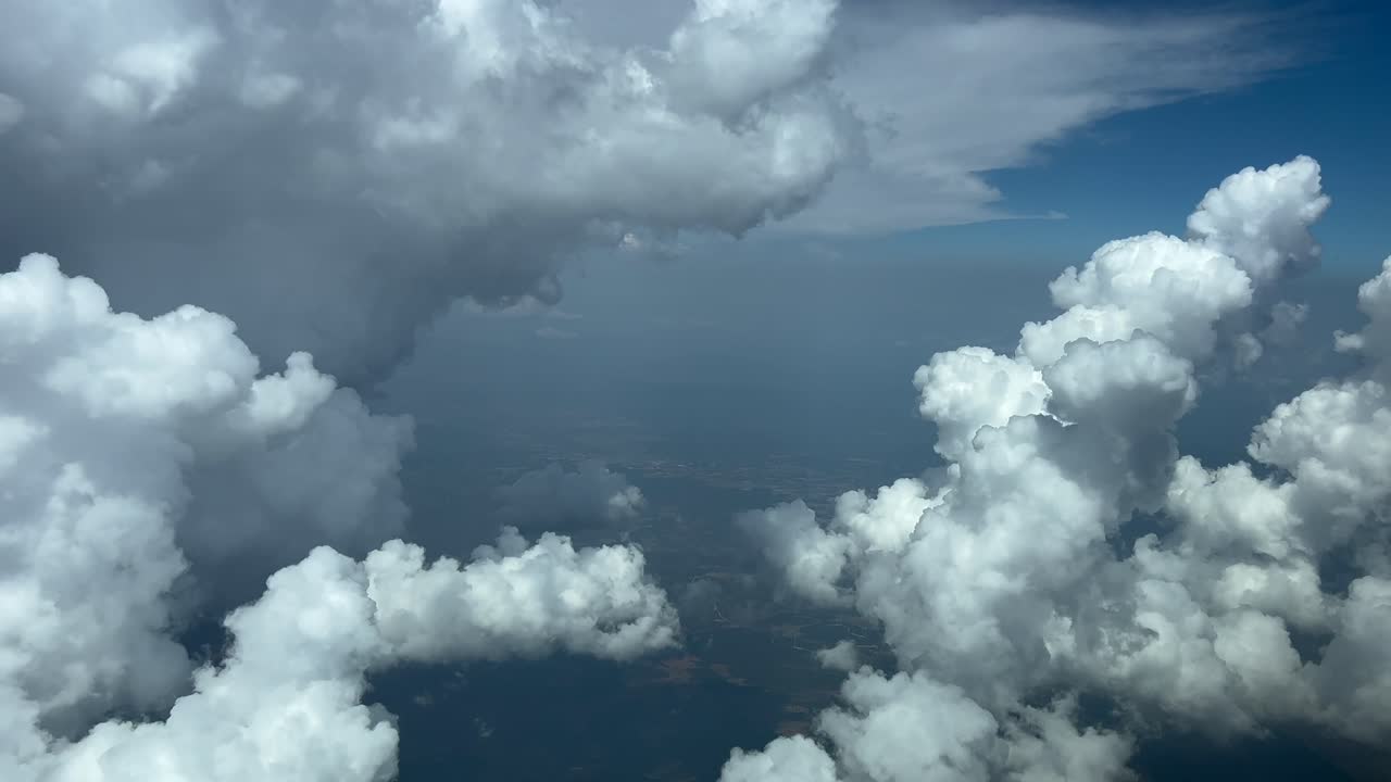 Immersive pilot’s perspective, POV FPV in a real time flight through a blue sky with a huge storm cloud on the left hand side and some beautiful cottony clouds bellow