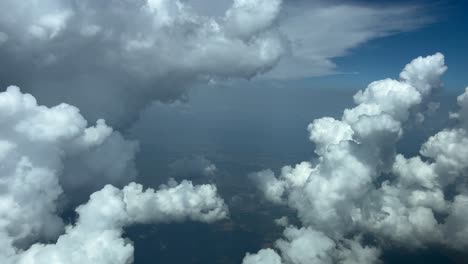 perspectiva inmersiva del piloto, pov fpv en un vuelo en tiempo real a través de un cielo azul con una enorme nube de tormenta en el lado izquierdo y algunas hermosas nubes de algodón bajo