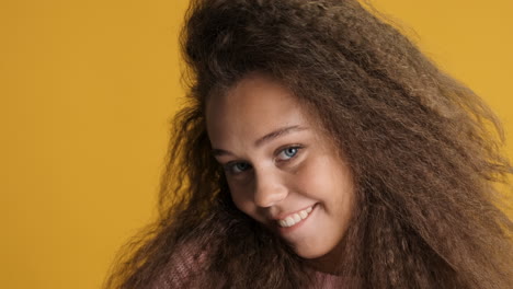 caucasian curly haired woman winking and smiling to the camera.