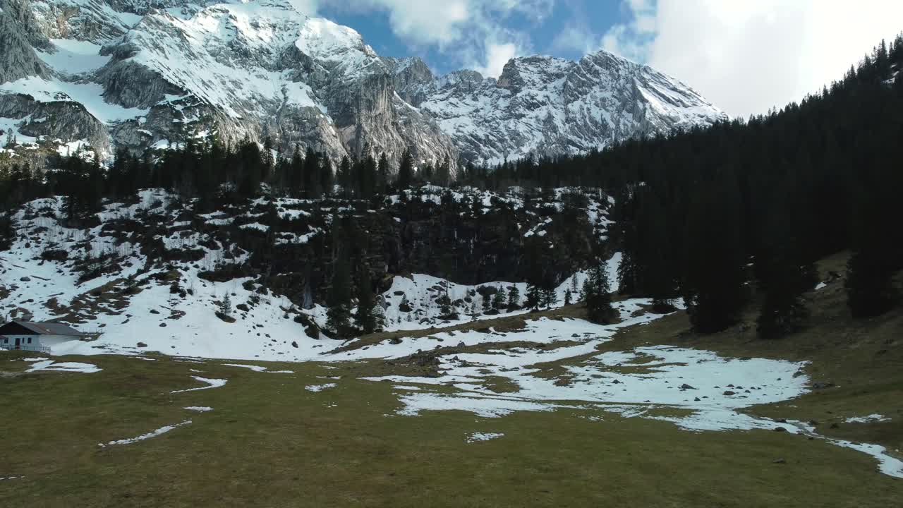 amplio vuelo panorámico hacia la cima de una montaña nevada de roca glaciar cerca del castillo de baviera elmau en los alpes austríacos bávaros en un día soleado a lo largo de árboles y bosques en la naturaleza con avalanchas bajando