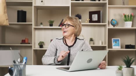 Ältere-Frau-Mit-Brille-Bestellt-Online-Essenslieferungen,-Während-Sie-Hinter-Ihrem-Laptop-Sitzt,-Und-Der-Kurier-Liefert-Es-Schnell-Aus,-Was-Die-Frau-Beeindruckt-Und-Lächelnd-Zurücklässt