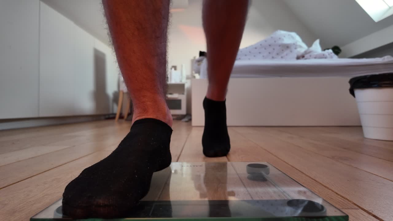 Foot in sock hovering above glass digital scale at home