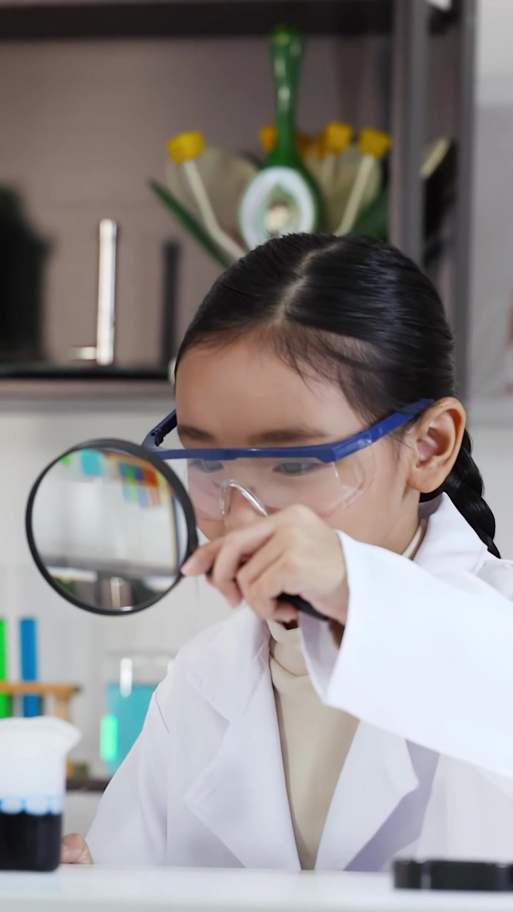 Giovani ragazze asiatiche conducono un esperimento scientifico con una lente d'ingrandimento.