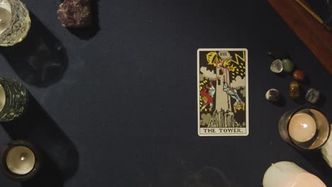 overhead shot of person giving tarot card reading with the tower card on lying on table