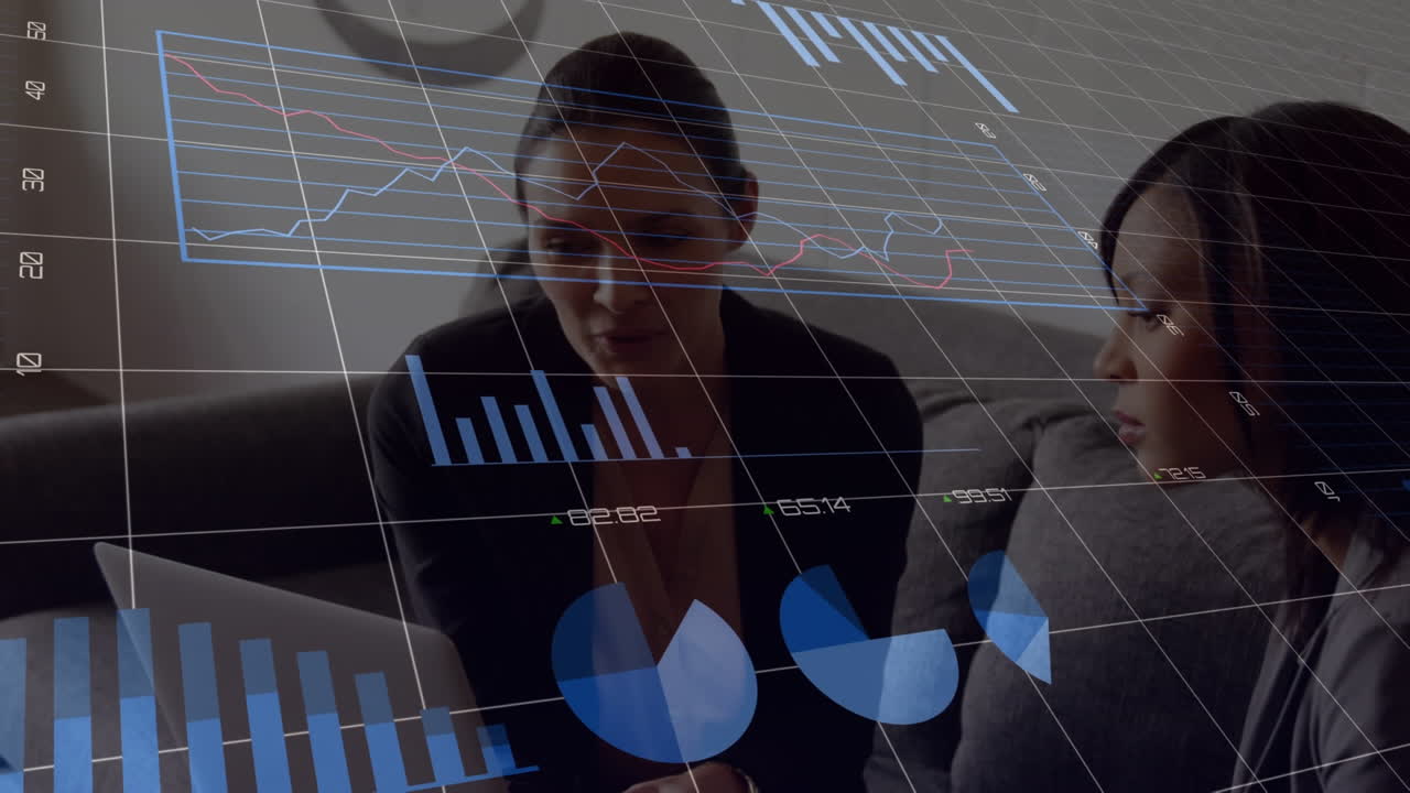 Animation of data processing over two diverse businesswomen discussing over laptop at office