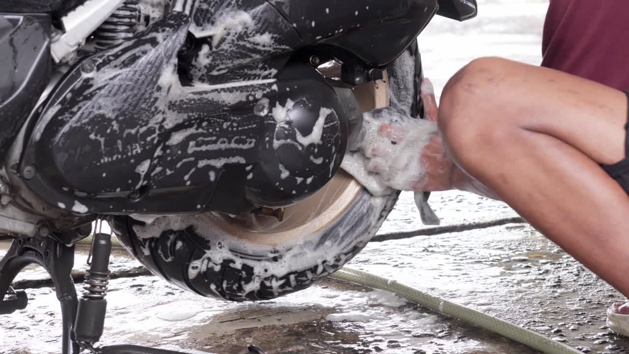 Person Cleaning Washing Motorcycle Wheel With Water and Soap, Close-Up