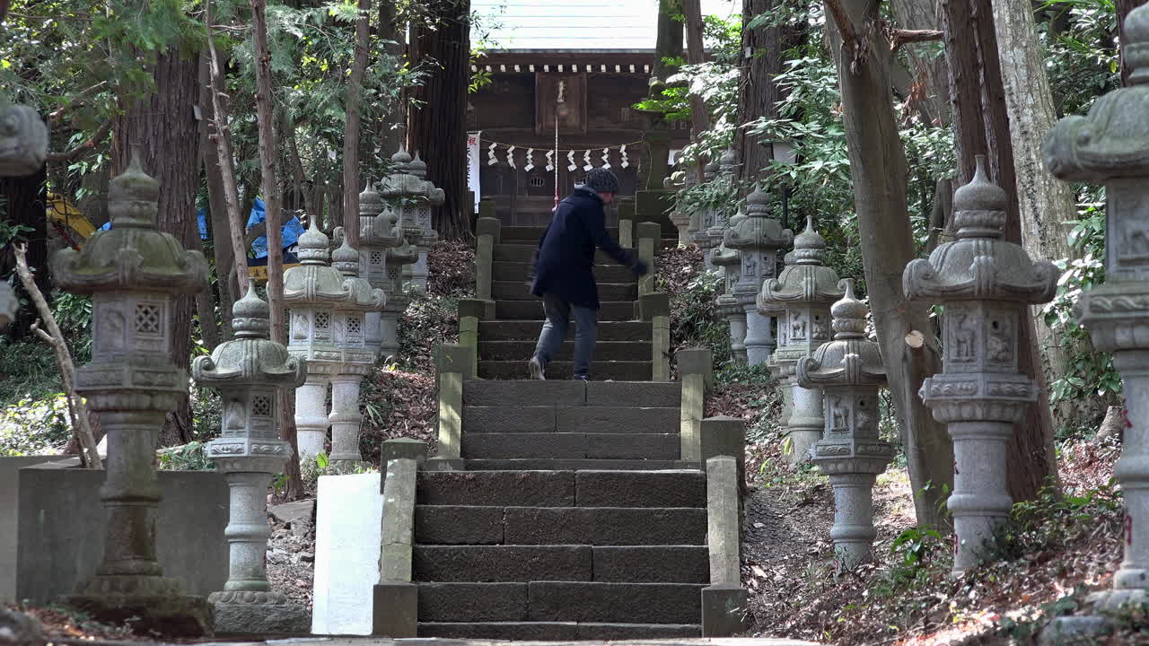 un hombre caucásico llega a la cima de la escalera en un templo tradicional japonés durante el día