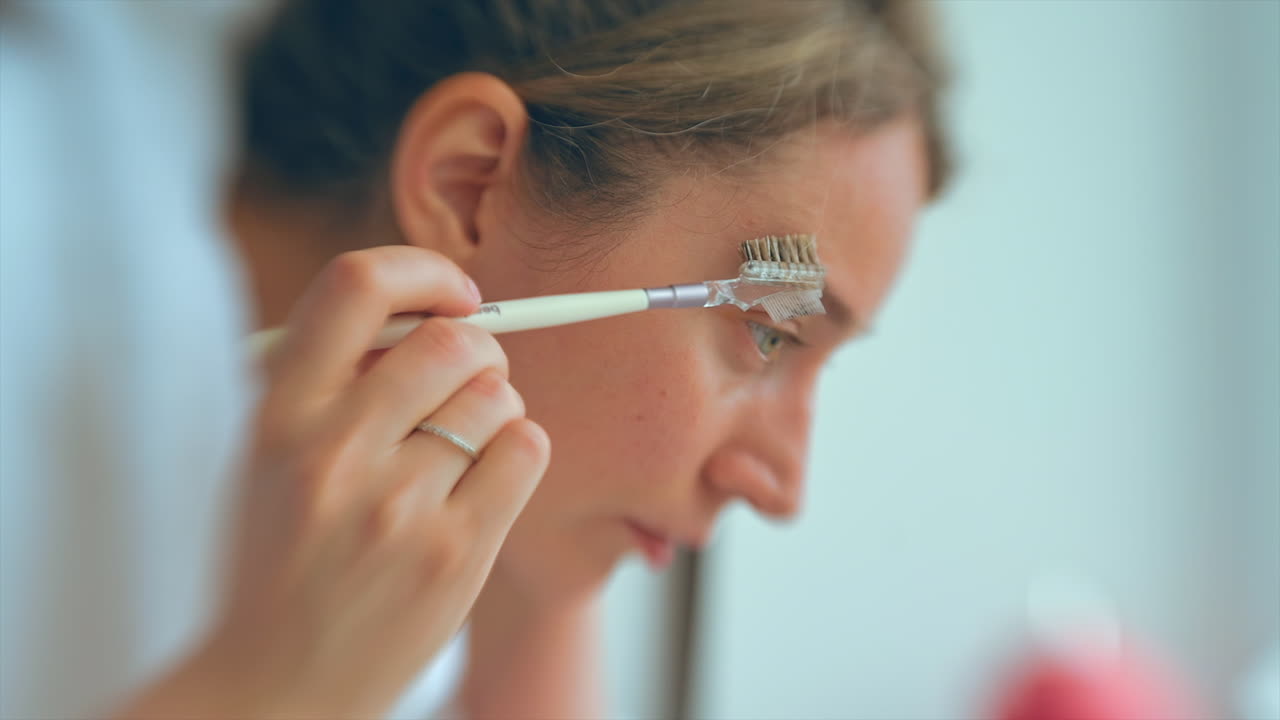 Woman shaping her eyebrows in the bathroom