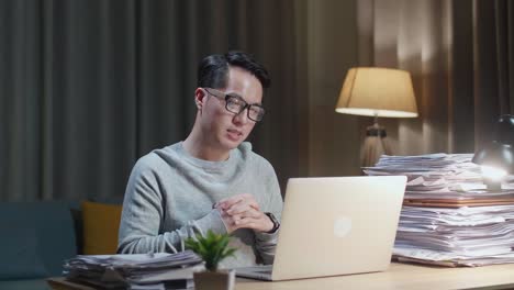 asian man explaining work while having video call on laptop at home