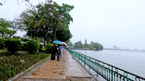 people walking with umbrellas by a river