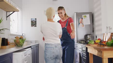 feliz pareja de mujeres diversas abrazándose y bailando juntos en la cocina