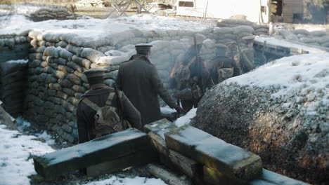 A-snow-covered-First-World-War-tench,-cold-British-WW1-army-soldiers-walk-back-from-the-front-line-in-France