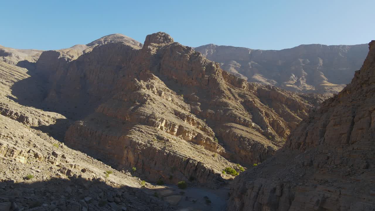 4K Bird's eye view from drone going through rocky valleys of Jabal Bil Ays-Jais Mountian during sunrise, The UAE's highest peak, Jebel Jais of Ras Al Khaimah, United Arab Emirates