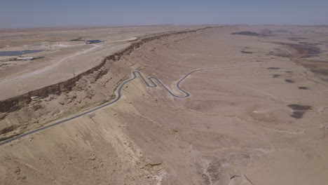 Blick-Auf-Ein-Wunderschönes-Trockenes-Wüstengebiet-Mit-Einer-Kurvenreichen-Straße,-Die-Aus-Einem-Krater-Herausragt