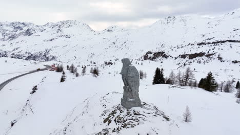 eagle sculpture of stone overlooking the simplon pass with in the background the high swiss alps covered by snow