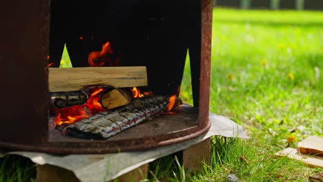 wood burns in open fire pit for outdoor soup cooking during daylight in nature setting, slow motion