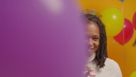 retrato de estudio de una mujer con una cinta para la cabeza de cumpleaños celebrando con globos y soplador de fiesta 2