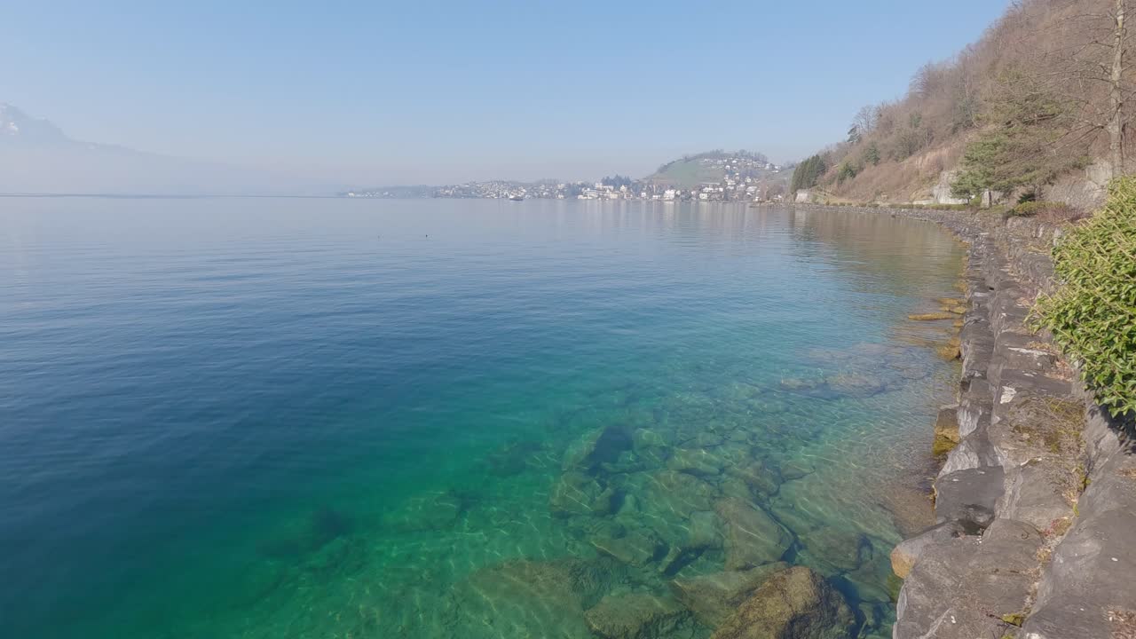 Misty morning on lake Lucerne in Switzerland with view towards the beginning of the lake and the street nearby