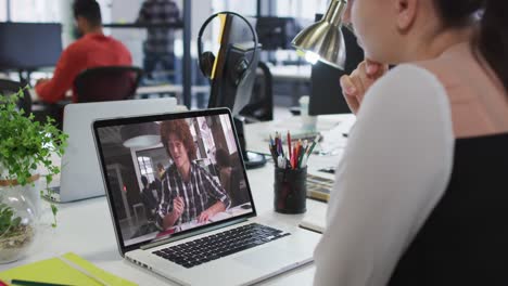 Caucasian-woman-having-a-video-call-with-male-colleague-on-laptop-at-office