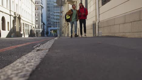 dos felices amigos de raza mixta caminando y hablando en la calle