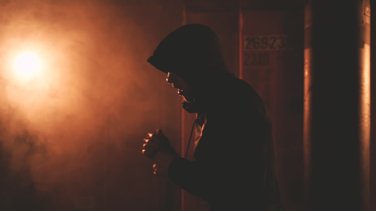 боксер в толстовке разогревается, пробивая воздух