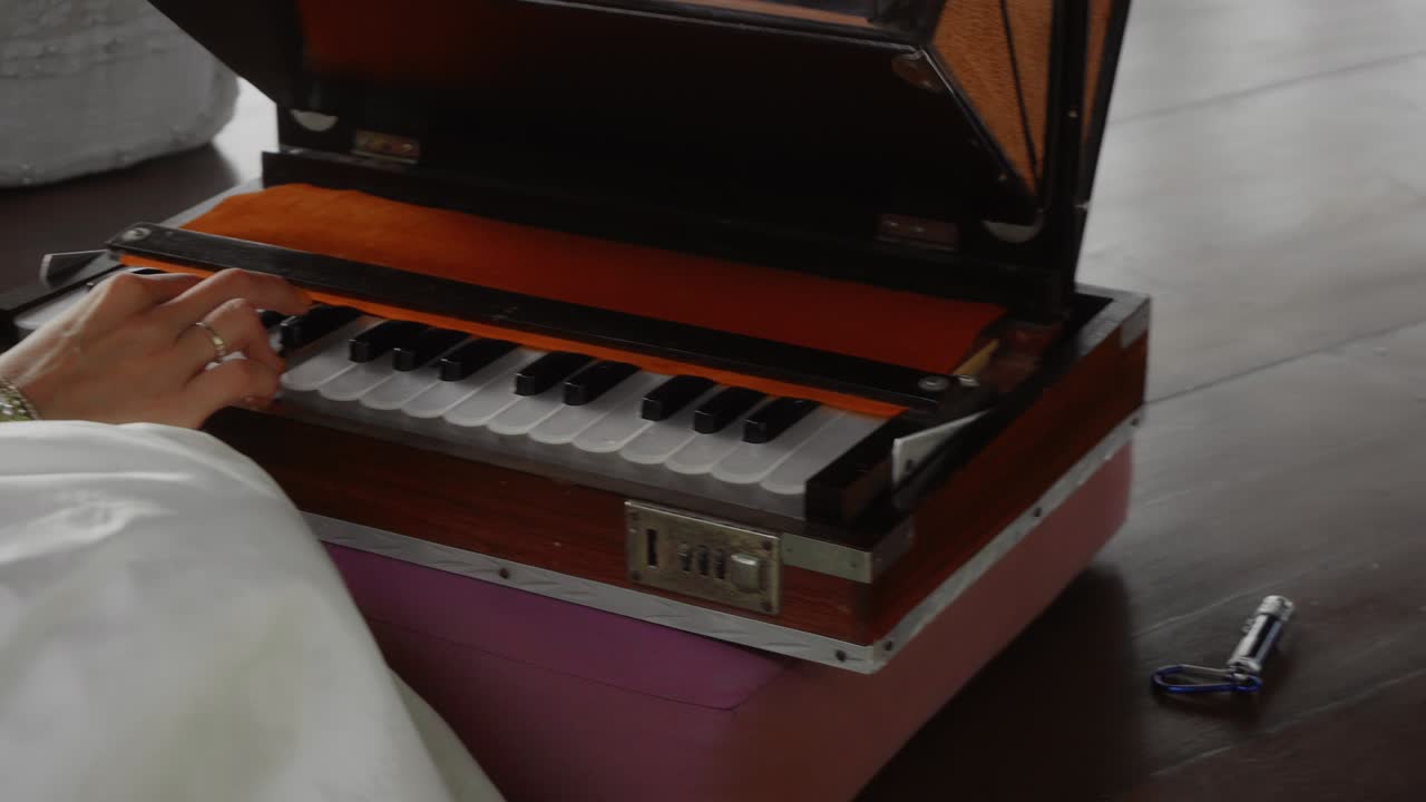 girl sitting on a wooden floor and playing a keyboard ethnic Indian instrument harmonium