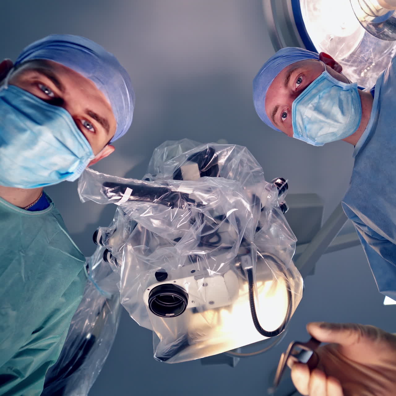 Surgeons faces in medical masks. Professional doctors perform an operation with medical instruments in the operating room. View from below.