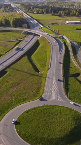 highway road with multi level junction and green landscape of latvia, aerial vertical view