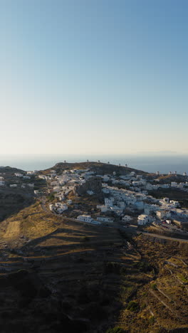 aerial orbit around the medieval castle of amorgos in chora during sunrise. the iconic cycladic windmills in the background. vertical